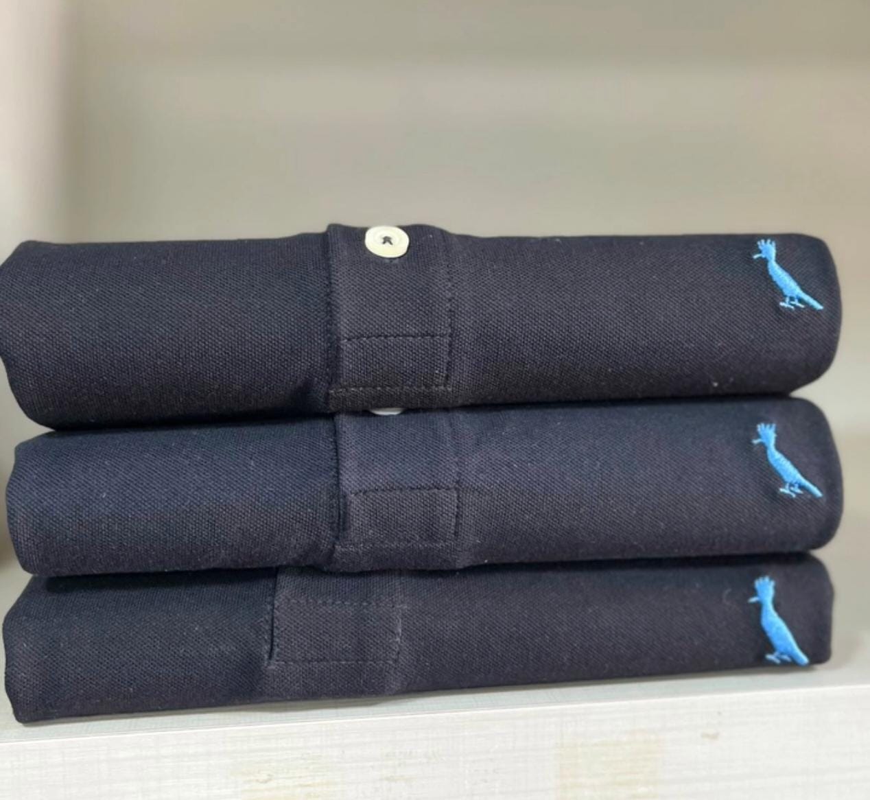 Camisas polo azul-marinho dobradas na Código Homem